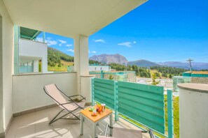 Ein Balkon mit Tisch, Stühlen und Bergblick.