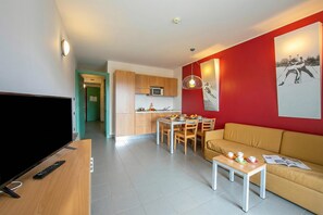 Una sala de estar moderna con televisor, sofá y comedor.