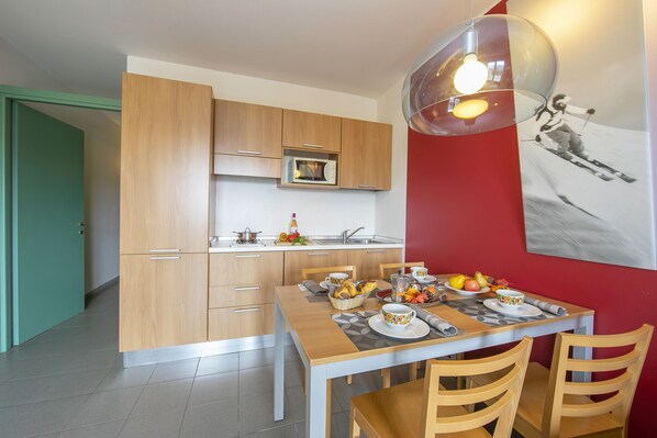 Eine moderne Küche mit Holzausstattung, einer Mikrowelle und einem Essbereich mit Tisch für zwei Personen.