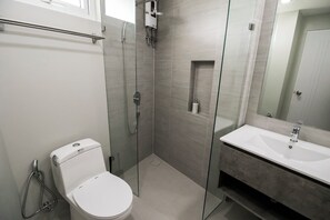 Features a sleek toilet, spacious shower with glass enclosure, and a large mirror above the sink.
