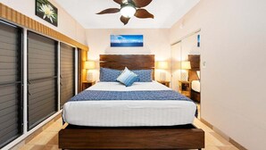 Un dormitorio con cama, ventilador de techo, mesita de noche y lámpara de pared.