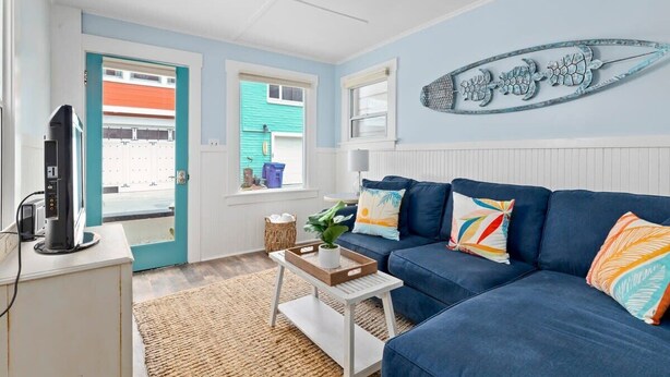 A living room with a blue sofa, a coffee table, a TV, and a wall decoration.