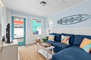 A living room with a blue sofa, a coffee table, a TV, and a wall decoration. - Capitola Beach Haven -Dog-friendly (Capitola)