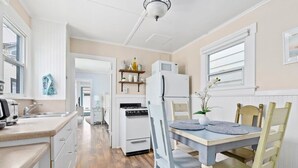 A kitchen with white cabinets, a stove, a refrigerator, and a dining table with chairs.