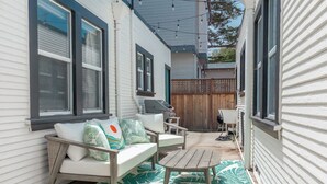 A patio with a white sofa, a wooden table, and a patterned rug.
