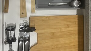 A kitchen drawer with wooden utensils, metal cutlery, and a cutting board. - Unique and Spacious 1BR Basement near Anthony Henday.  (Edmonton)