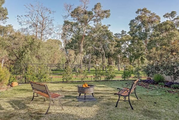 An outdoor seating area with two metal benches and a fire pit.