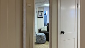 A hallway with a large mirror, a white door, and a small ottoman. - Make Victoria View your home base while exploring PNW! Garage to store your toys (Port Angeles)