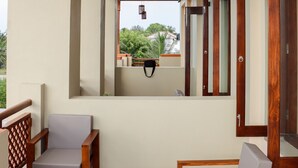 Een balkon met houten meubels, een tafel en uitzicht op groen.