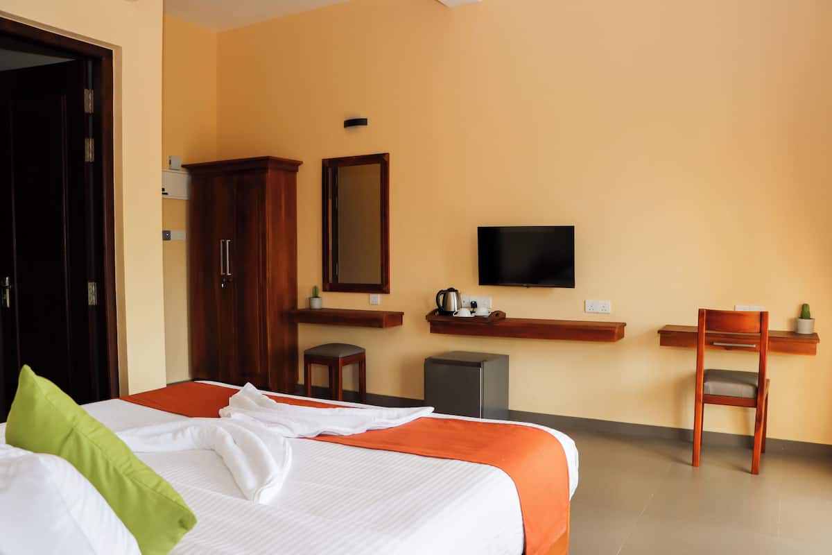 A hotel room with a bed, a desk, a chair, a television, and a wardrobe.
