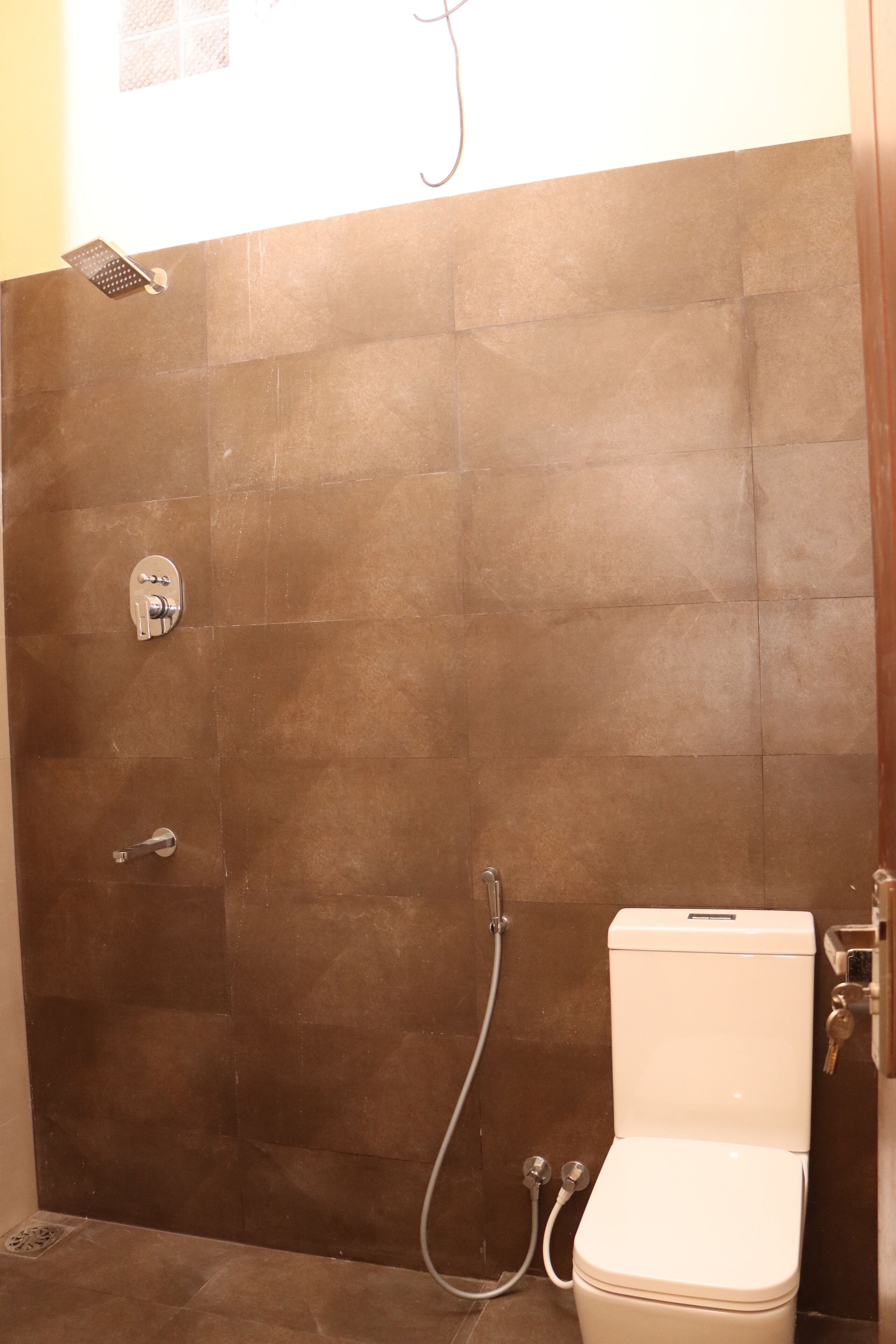 Een badkamer met douche, toilet en een muurkraan.