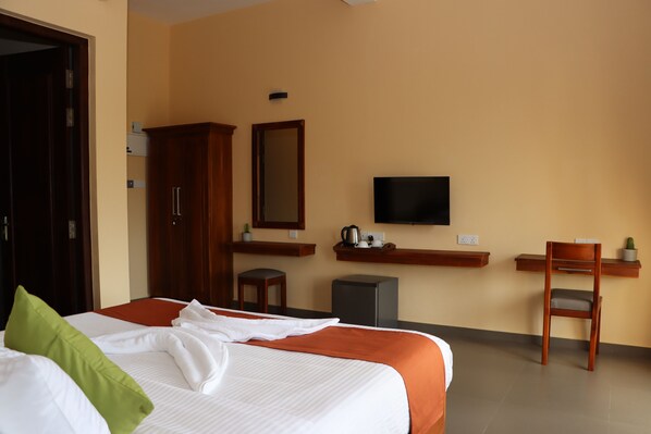 Una habitación de hotel con cama, escritorio, silla, televisor y armario.