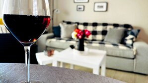 A glass of red wine on a table with a checkered sofa and a white coffee table in the background. - Cozy Snuggle- 2min To Beach, 6min Walk To Old Town (Chania)
