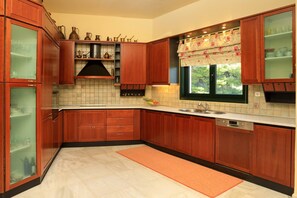 A kitchen with wooden cabinets, a tiled backsplash, a window with a floral curtain, and a stainless steel sink.