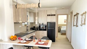 A modern kitchen with wooden cabinets, a black refrigerator, and a dining area with black chairs and a table set for two.