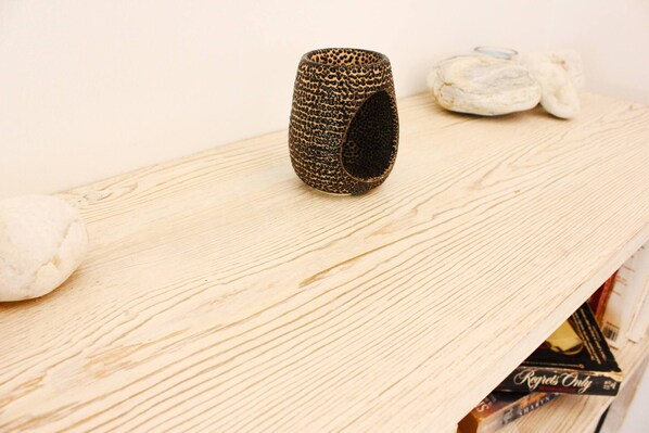 A textured ceramic mug on a wooden surface with a book and a ring.