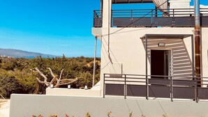 A modern building with a balcony, a staircase, and a view of the landscape.