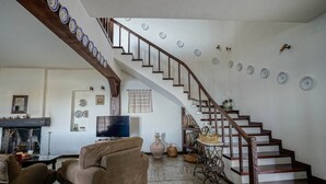 Una sala de estar con chimenea, un sofá, un televisor y una escalera adornada con placas decorativas.