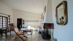 Amplia sala de estar con chimenea, un espejo grande y suelo de piedra.