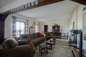 A living room with a large brown sofa, a wooden coffee table, and a fireplace. - Sonia Rustic Mansion - 5bd 30 Sec Walk To Beach! (Klimaki)