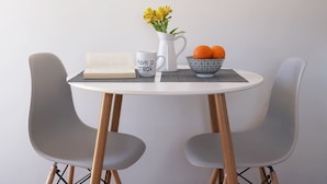 A round table with a book, a mug, a pitcher with flowers, and a bowl of oranges. - The Suite Spot - At The Heart Of The Old Town (Chania)