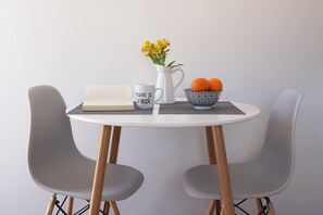 A round table with a book, a mug, a pitcher with flowers, and a bowl of oranges. - The Suite Spot - At The Heart Of The Old Town (Chania)