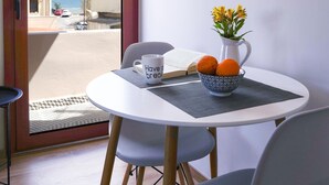 A dining area with a table, chairs, a bowl of fruit, a mug, and a vase of flowers. - The Suite Spot - At The Heart Of The Old Town (Chania)