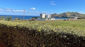 Una casa moderna de dos pisos con techo plano, ubicada en una colina cubierta de césped con vistas a un cuerpo de agua.