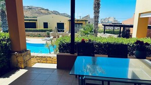 Un espacio al aire libre cubierto con piscina, paredes de piedra y vista a edificios en el fondo.