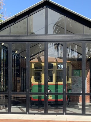 Eine Straßenbahnhaltestelle mit Glasüberdachung, eine Straßenbahn mit der Nummer 29 sowie eine weitere Straßenbahn in Grün und Gelb.