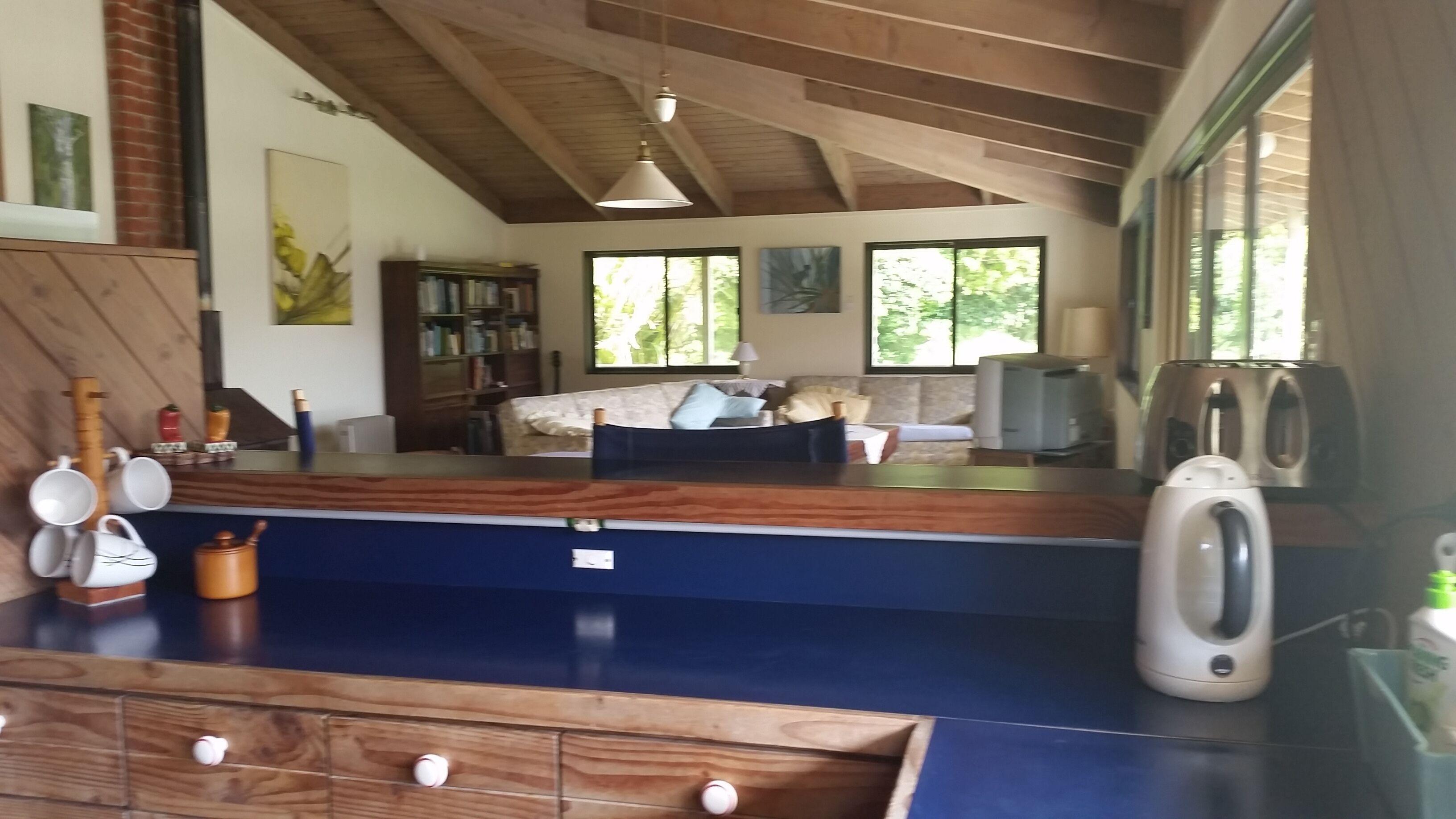 Een moderne woonkamer met een hoge plafond, houten balken, een bank, een salontafel en een televisie.