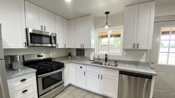 Una cocina moderna con armarios blancos, electrodomésticos de acero inoxidable y un piso con diseño de cuadros.