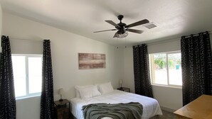 Un dormitorio con cama, ventilador de techo, mesita de noche, lámpara y cómoda.