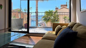 A balcony with a view of the sea, a sofa, and a glass table.