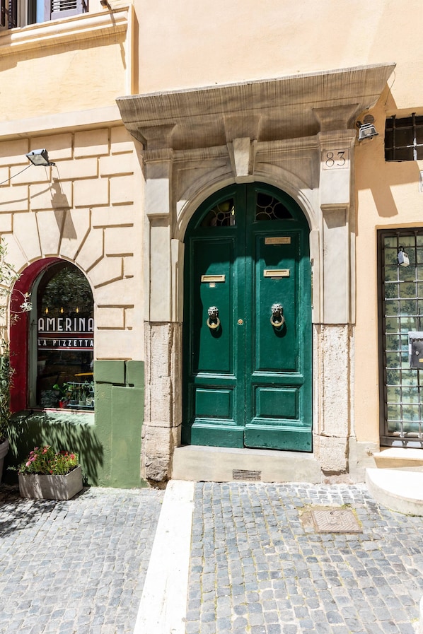 A building with a green double door and a sign that reads "AMERINA LA PIZZETTA".