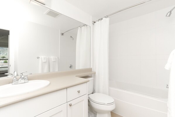 Un ba ño moderno con un lavamanos, espejo y retrete blancos.