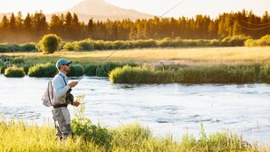 A man fishing by a river with a mountain in the background. - House on Metolius (Camp Sherman)