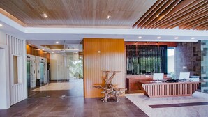 A modern lobby with a reception desk, a wooden decorative piece, and a glass partition.
