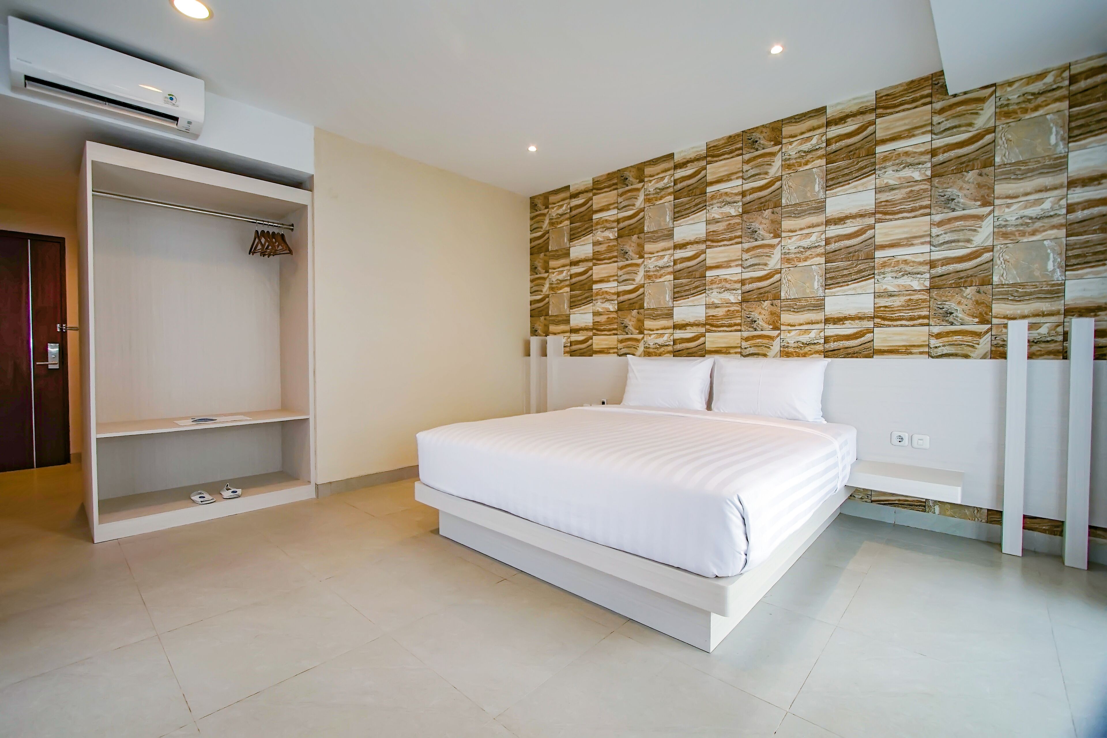 A bedroom with a bed, a wardrobe, and a wall with a patterned design.