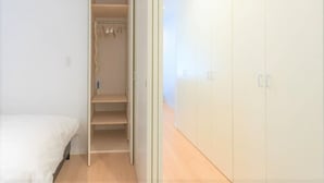A bedroom with a bed, a closet with hanging space, and a wardrobe with doors. - SALON Shibuya 4B (Tokyo)