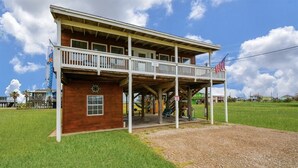 A wooden building with a balcony, a flag, and a sign.