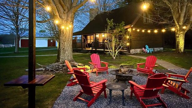 Une terrasse avec des fauteuils Adirondack rouges, un foyer et des guirlandes lumineuses.