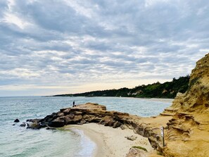 A coastal beach with rocky formations, clear water, and a distant view of the sea. - Bay Rd | Kids & Pet Friendly | Free Parking (Cheltenham)