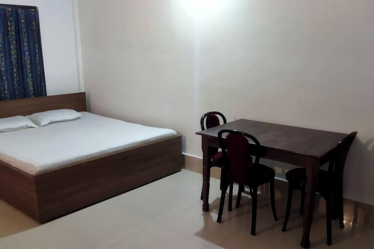 Un dormitorio con una cama, una mesita y dos sillas.