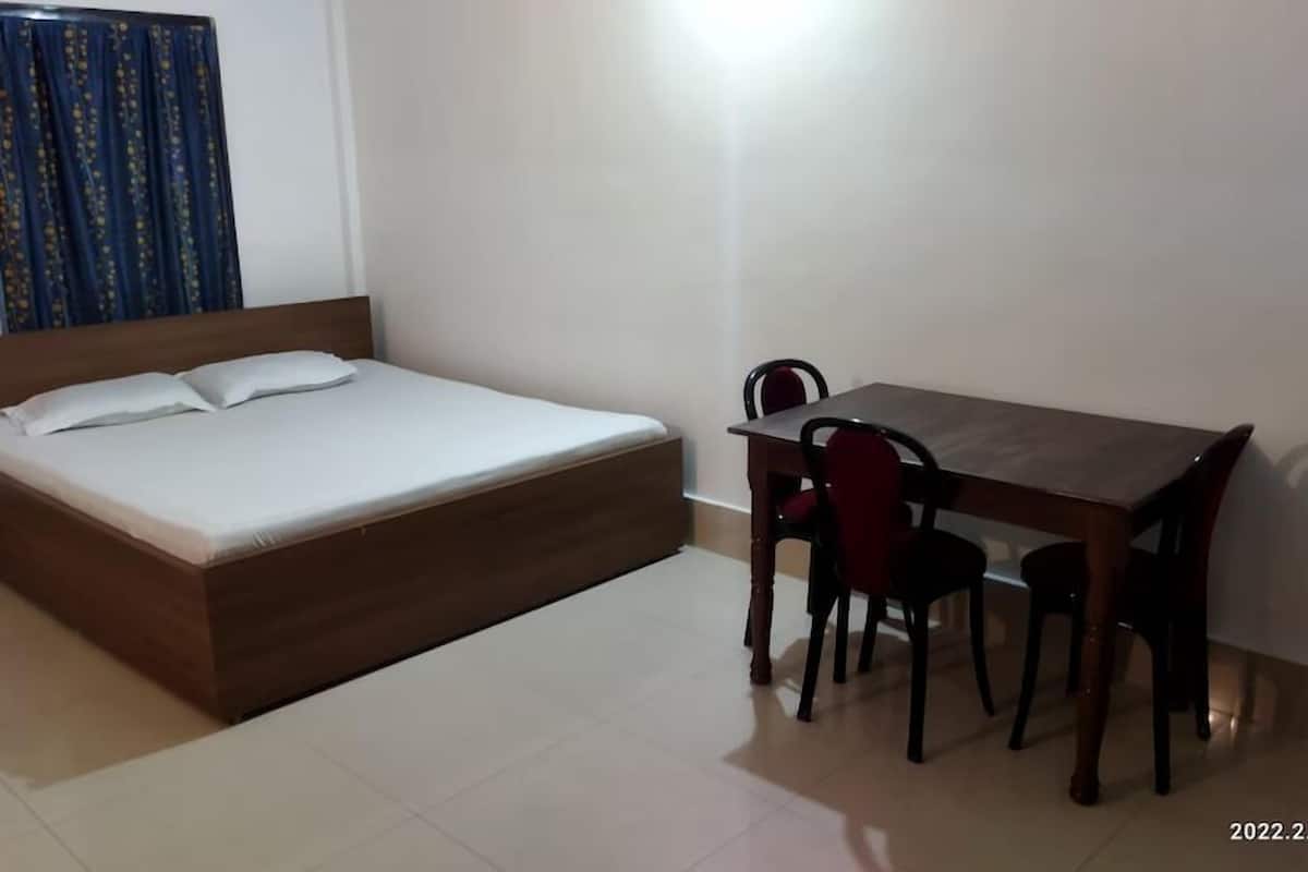 Un dormitorio con una cama, una mesa de madera y dos sillas.