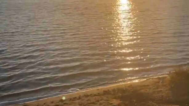 A beach with a calm sea and a sunset in the background. - Creekside Stay in Walker, MN (Walker)