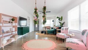 Un salon moderne avec un canapé vert, un fauteuil rose et un tapis rond.