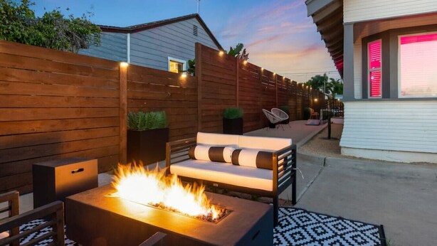 Une terrasse dotée d’un foyer extérieur, de sièges et d’une clôture en bois.