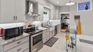 A modern kitchen with grey cabinets, stainless steel appliances, and a marble countertop. - Downtown Executive Retreat (Hickory)