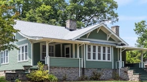 A green house with a stone foundation, a porch, and a chimney. - Downtown Executive Retreat (Hickory)